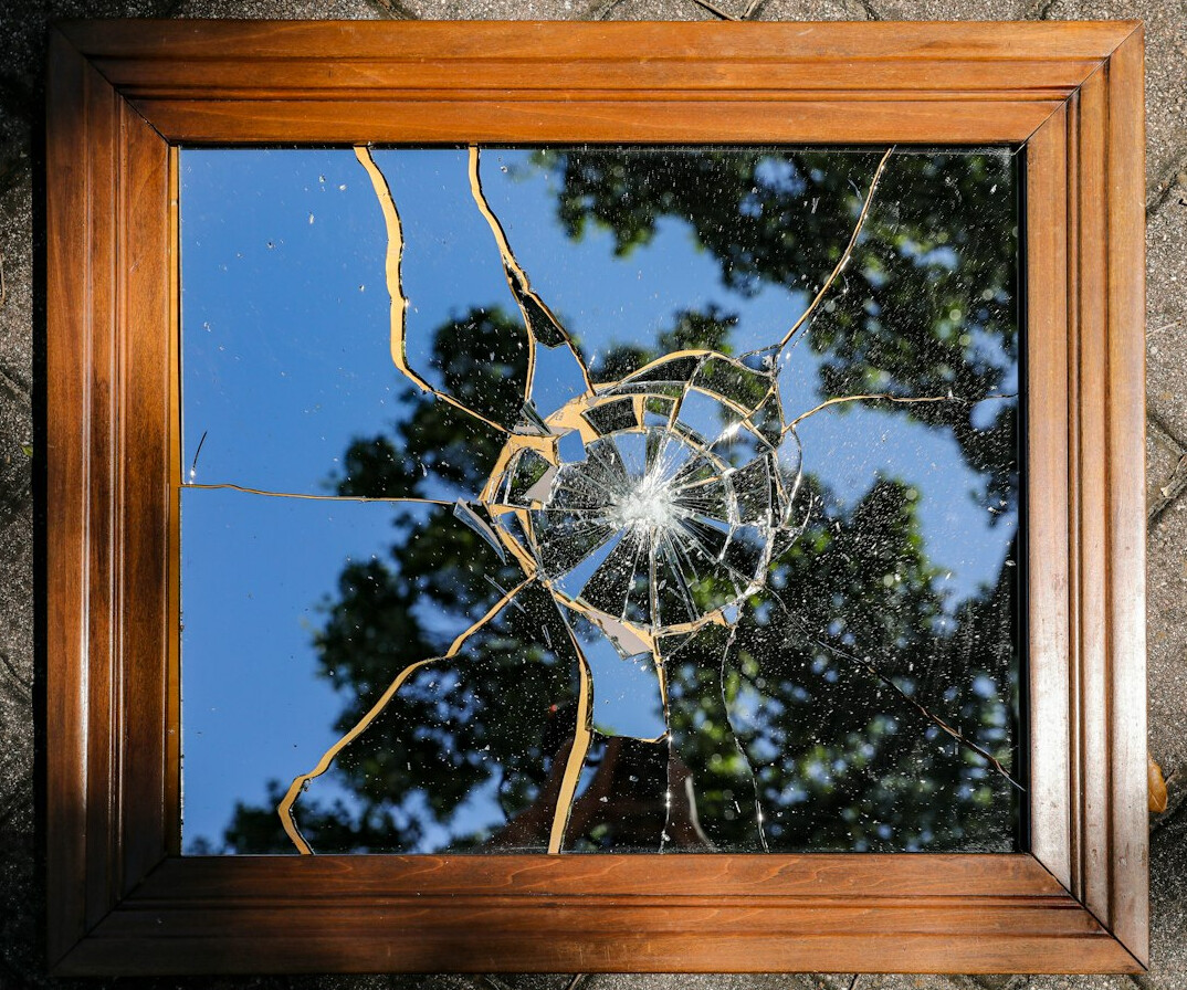 Fragmented reflection in a broken mirror suggesting divided identity