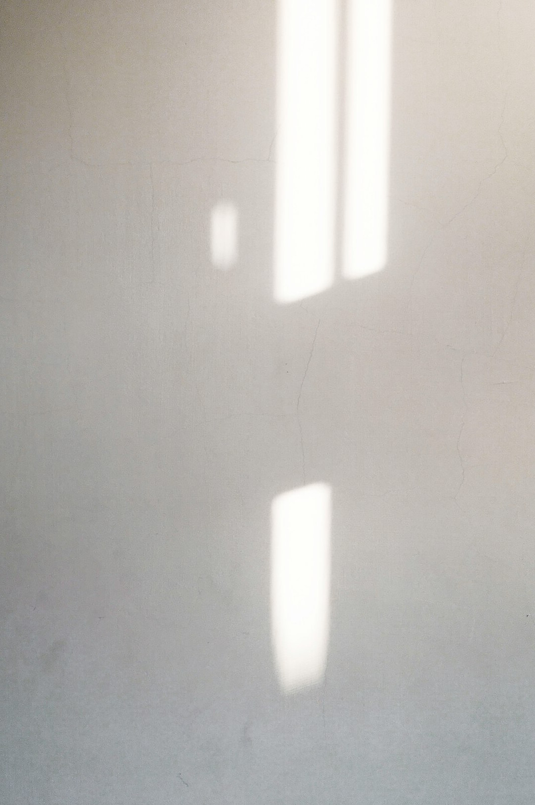 Long architectural shadow cast across a plain concrete wall